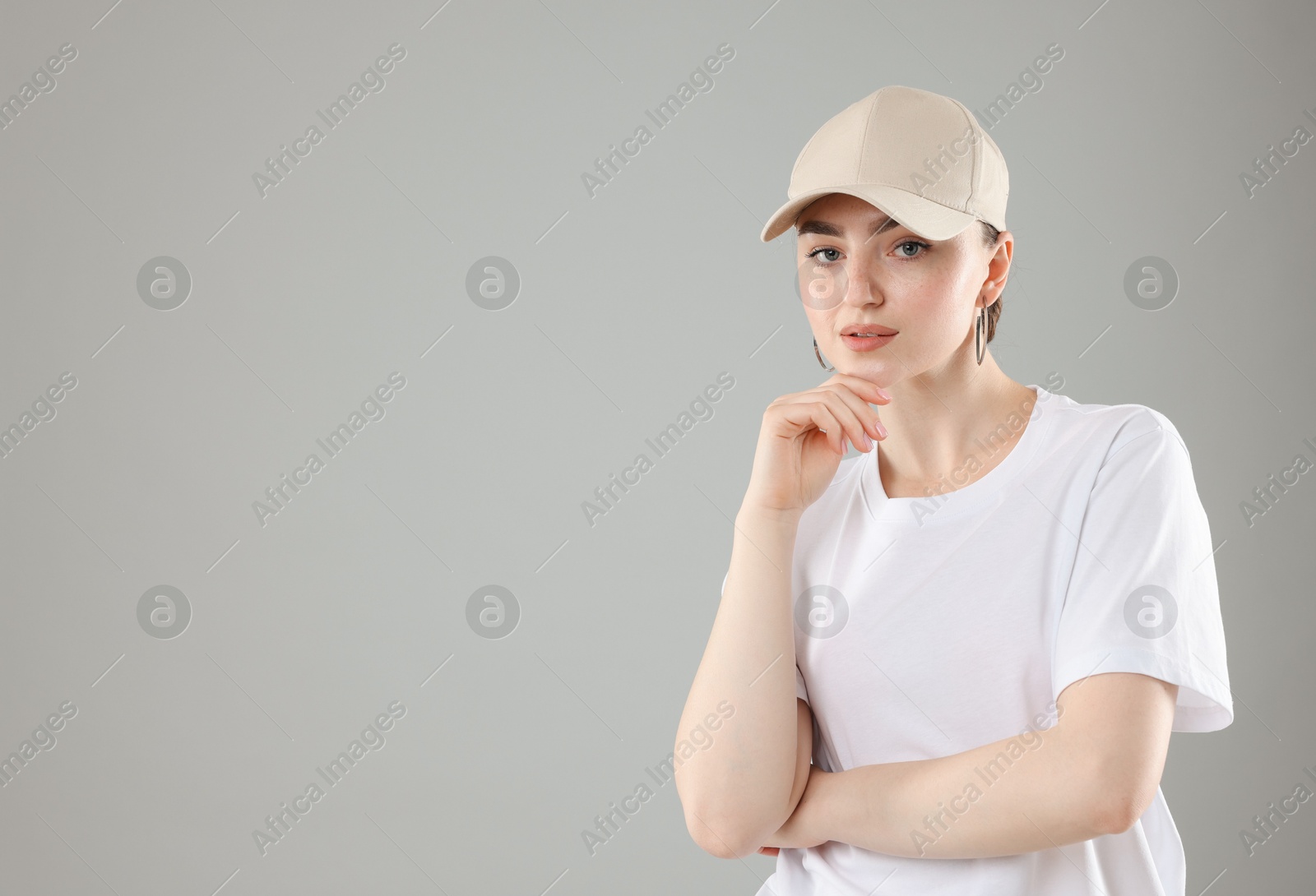 Photo of Portrait of beautiful woman in stylish baseball hat on grey background. Space for text