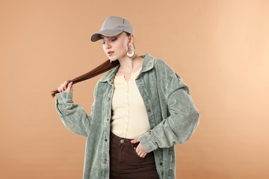 Photo of Beautiful woman in stylish baseball hat on beige background