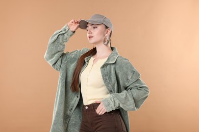 Photo of Beautiful woman in stylish baseball hat on beige background