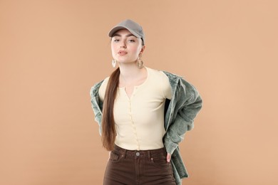 Photo of Portrait of beautiful woman in stylish baseball hat on beige background