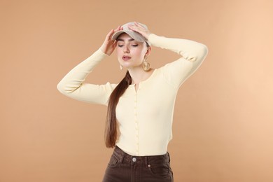 Photo of Beautiful woman in stylish baseball hat posing on beige background