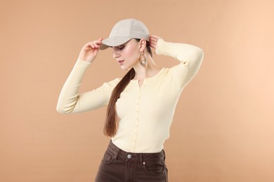 Photo of Beautiful woman in stylish baseball hat posing on beige background