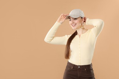 Photo of Smiling woman in stylish baseball hat on beige background. Space for text