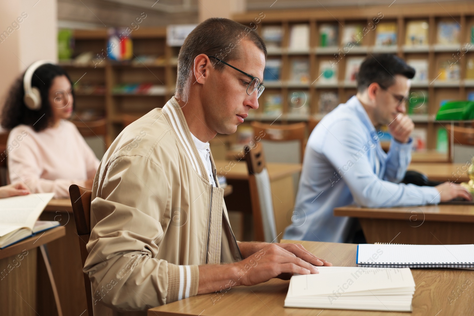 People studying at desks in public library, selective focus Photo of People studying at desks in public library, selective focus