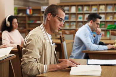 Photo of People studying at desks in public library, selective focus
