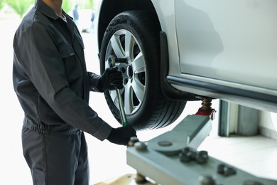 Photo of Mechanic changing tire at car service, closeup