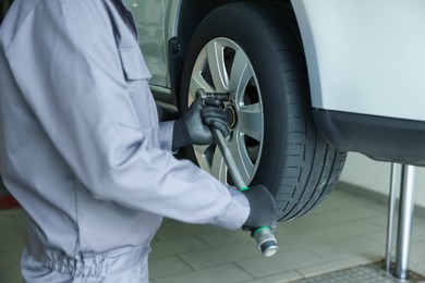 Photo of Mechanic changing tire at car service, closeup