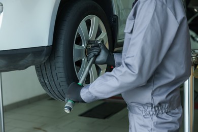 Photo of Mechanic changing tire at car service, closeup