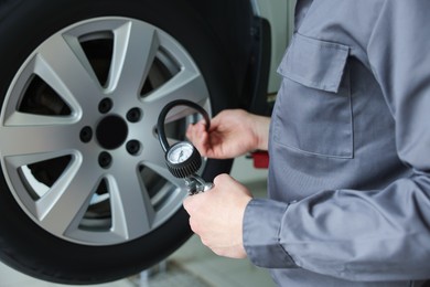 Photo of Mechanic inflating new tire at car service, closeup