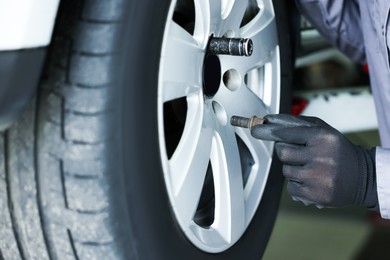 Photo of Mechanic changing tire at car service, closeup