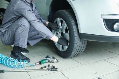 Photo of Mechanic changing tire at car service, closeup