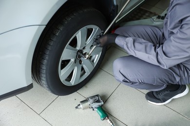 Photo of Mechanic changing tire at car service, closeup