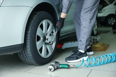 Photo of Mechanic changing tire at car service, closeup