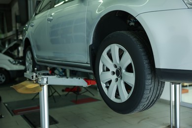 Photo of Lifted automobile during tire change at car service, closeup