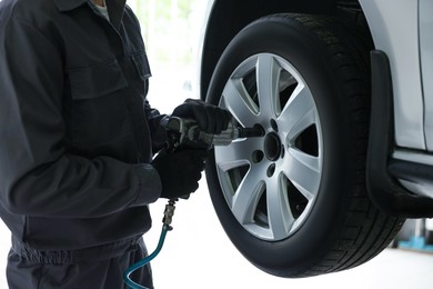 Photo of Mechanic changing tire at car service, closeup