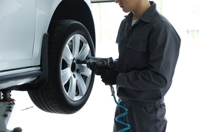 Photo of Mechanic changing tire at car service, closeup