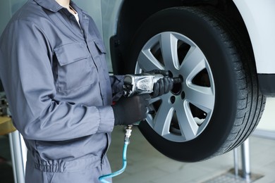 Photo of Mechanic changing tire at car service, closeup