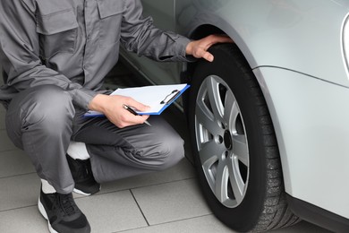 Photo of Mechanic checking tire after change at car service, closeup