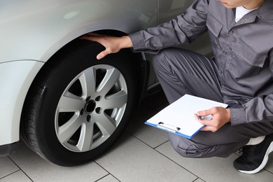 Photo of Mechanic checking tire after change at car service, closeup