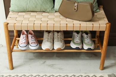 Photo of Different footwear on bench indoors. Shoe storage