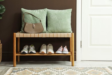 Photo of Different footwear on bench indoors. Shoe storage