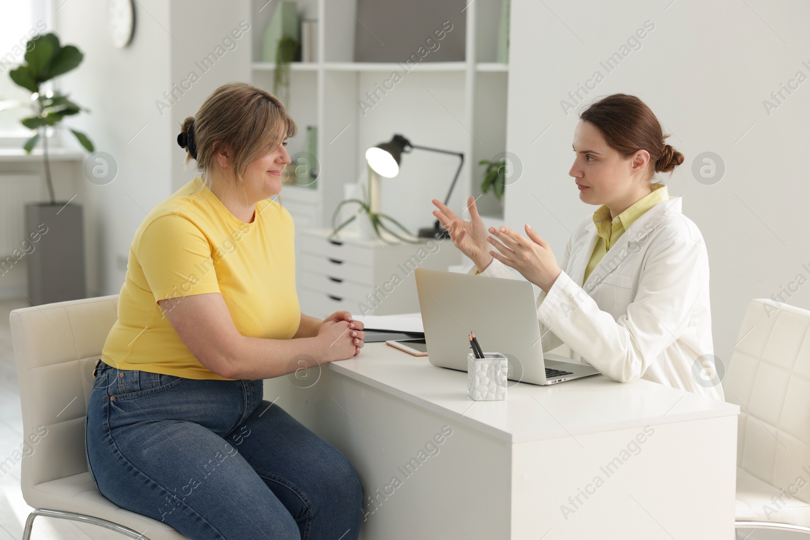 Photo of Weight loss. Nutritionist consulting overweight woman at white desk in clinic
