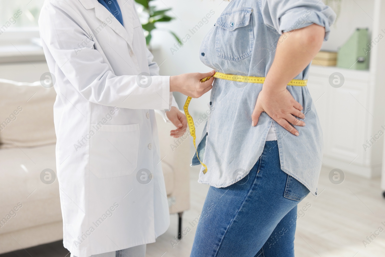 Weight loss. Nutritionist measuring overweight woman's waist with tape in clinic, closeup Photo of Weight loss. Nutritionist measuring overweight woman's waist with tape in clinic, closeup