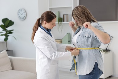 Photo of Weight loss. Nutritionist measuring overweight woman's waist with tape in clinic
