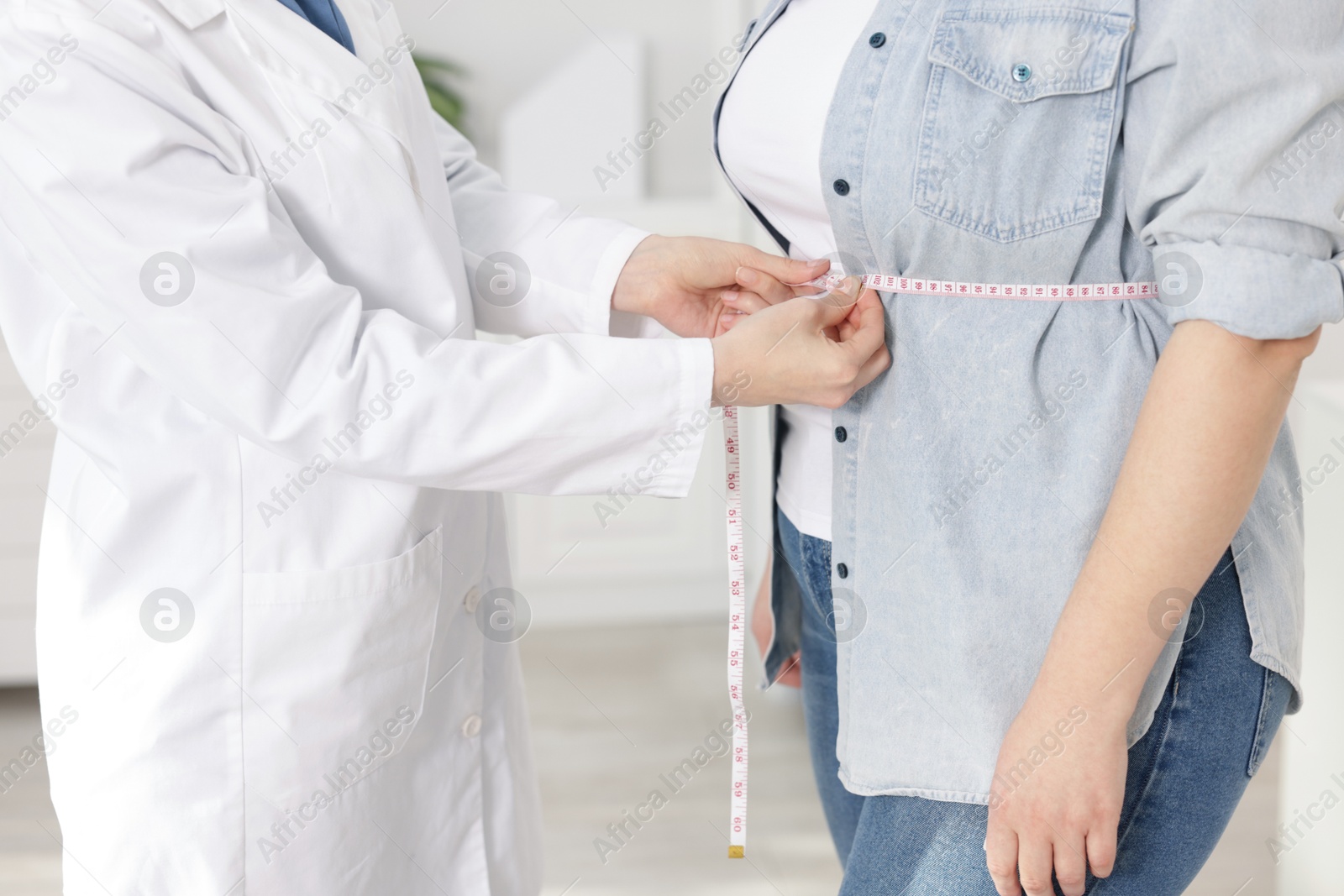 Weight loss. Nutritionist measuring overweight woman's waist with tape in clinic, closeup Photo of Weight loss. Nutritionist measuring overweight woman's waist with tape in clinic, closeup