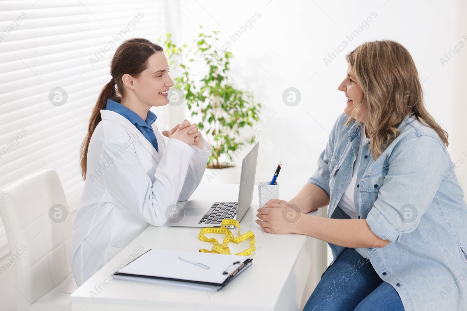 Photo of Weight loss. Nutritionist consulting overweight woman at white desk in clinic