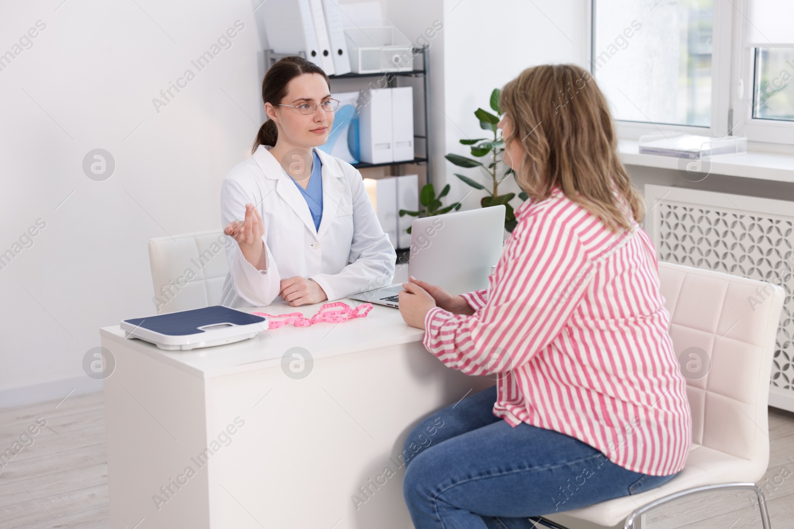 Photo of Weight loss. Nutritionist consulting overweight woman in clinic