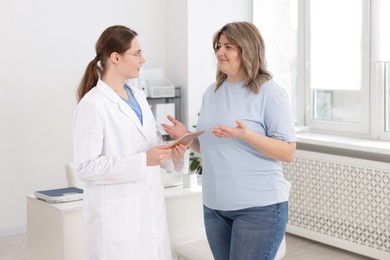 Photo of Weight loss. Nutritionist consulting overweight woman in clinic