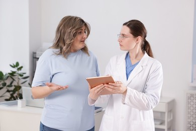 Photo of Weight loss. Nutritionist consulting overweight woman in clinic