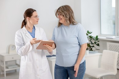 Photo of Weight loss. Nutritionist consulting overweight woman in clinic