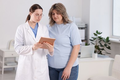 Photo of Weight loss. Nutritionist consulting overweight woman in clinic
