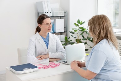 Photo of Weight loss. Nutritionist consulting overweight woman at white desk in clinic