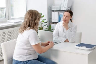Photo of Weight loss. Nutritionist consulting overweight woman at white desk in clinic