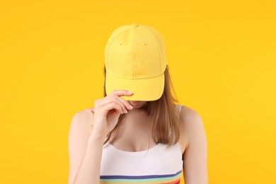 Photo of Young woman wearing stylish baseball hat on yellow background