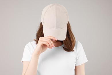 Photo of Young woman wearing stylish beige baseball hat on light grey background