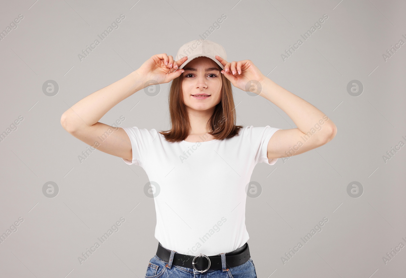 Young woman wearing stylish beige baseball hat on light grey background Photo of Young woman wearing stylish beige baseball hat on light grey background