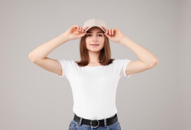 Photo of Young woman wearing stylish beige baseball hat on light grey background