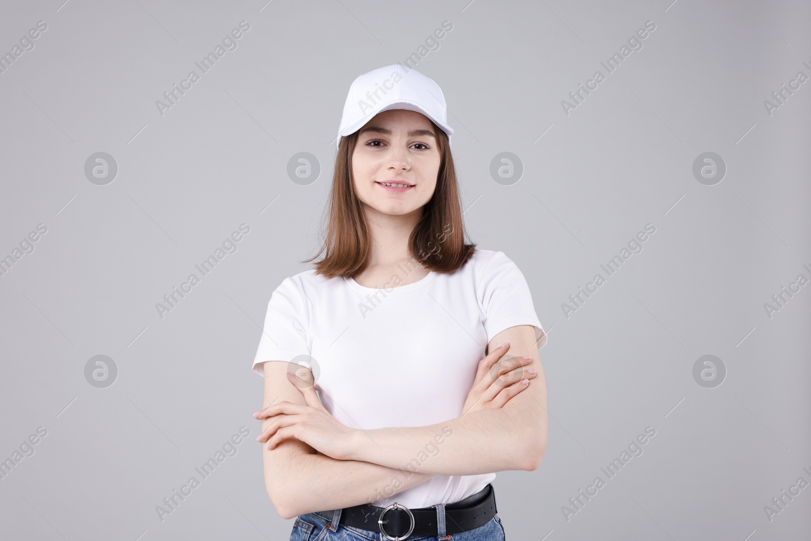 Young woman wearing stylish white baseball hat on light grey background Photo of Young woman wearing stylish white baseball hat on light grey background