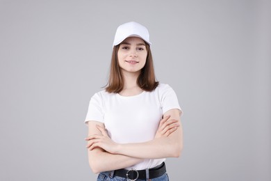 Photo of Young woman wearing stylish white baseball hat on light grey background