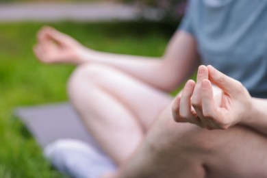 Photo of Young man practicing yoga on mat in park, closeup