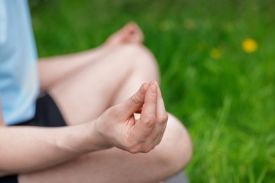 Photo of Young man practicing yoga on mat in park, closeup