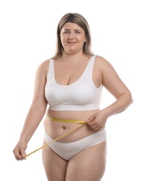 Photo of Weight loss. Plus size woman measuring waist with tape on white background