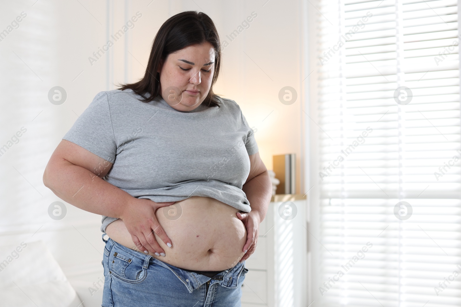Woman with excessive belly fat indoors, space for text. Overweight problem Photo of Woman with excessive belly fat indoors, space for text. Overweight problem