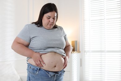 Photo of Woman with excessive belly fat indoors, space for text. Overweight problem