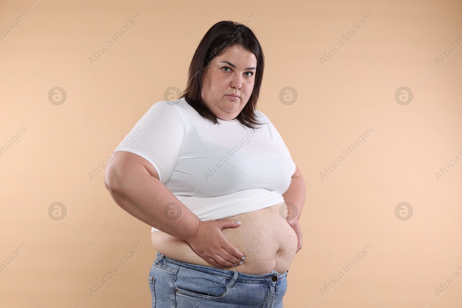 Woman with excessive belly fat on beige background Photo of Woman with excessive belly fat on beige background