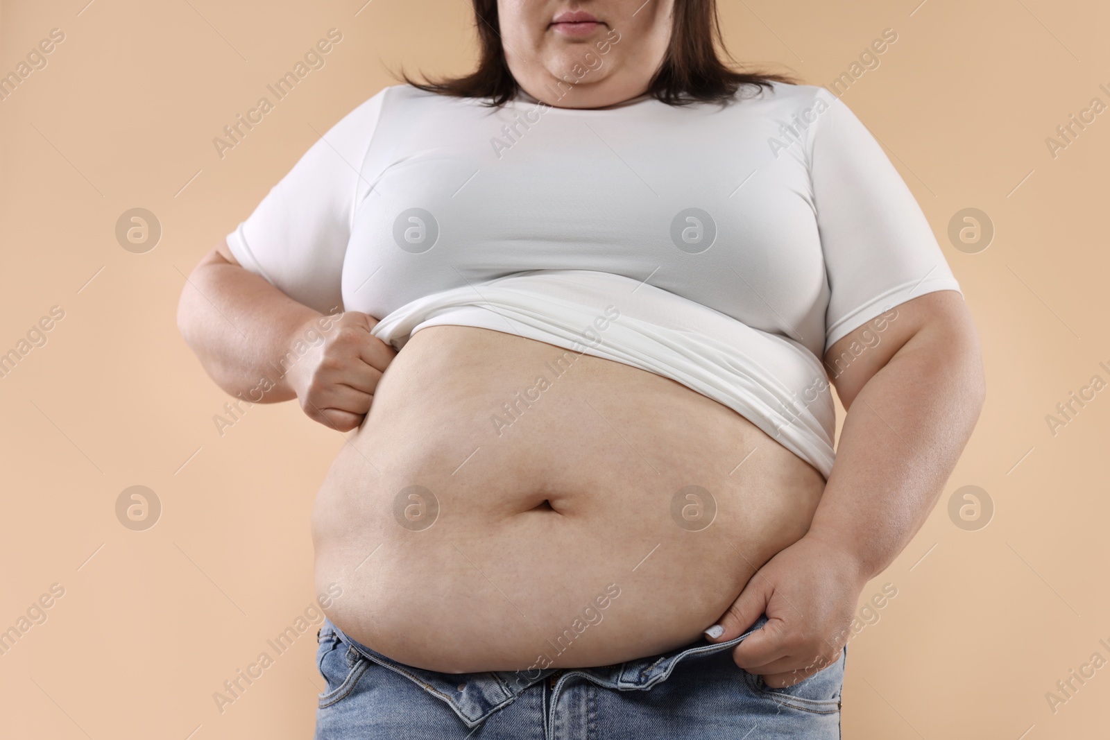 Woman with excessive belly fat on beige background, closeup Photo of Woman with excessive belly fat on beige background, closeup